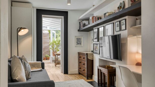 A modern living room with a sofa, a coffee table, a TV, and a bookshelf.