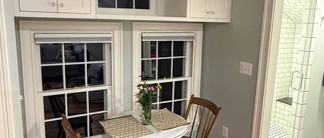 Una cocina con suelo de madera, armarios blancos y una mesa de comedor con sillas.
