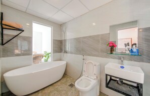 Une salle de bain moderne avec une baignoire sur pieds, des toilettes, un lavabo et une douche.