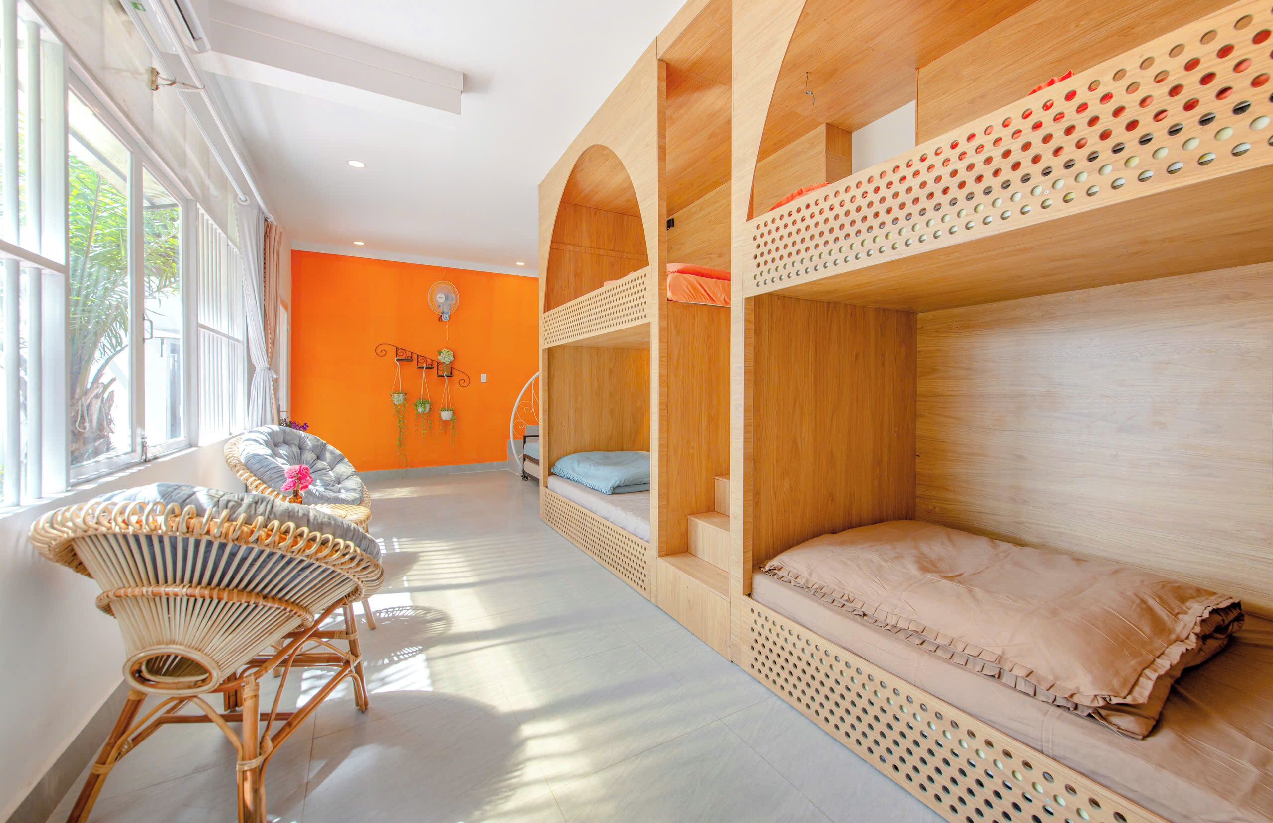 A room with bunk beds, a wicker chair, and a view of greenery outside.