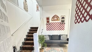 Una escalera con alfombra estampada que lleva a una sala de estar con un sofá y decoración mural.