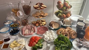 Un bufé de desayuno con diversas opciones de comida, incluyendo pan, bollería, frutas, huevos y verduras.