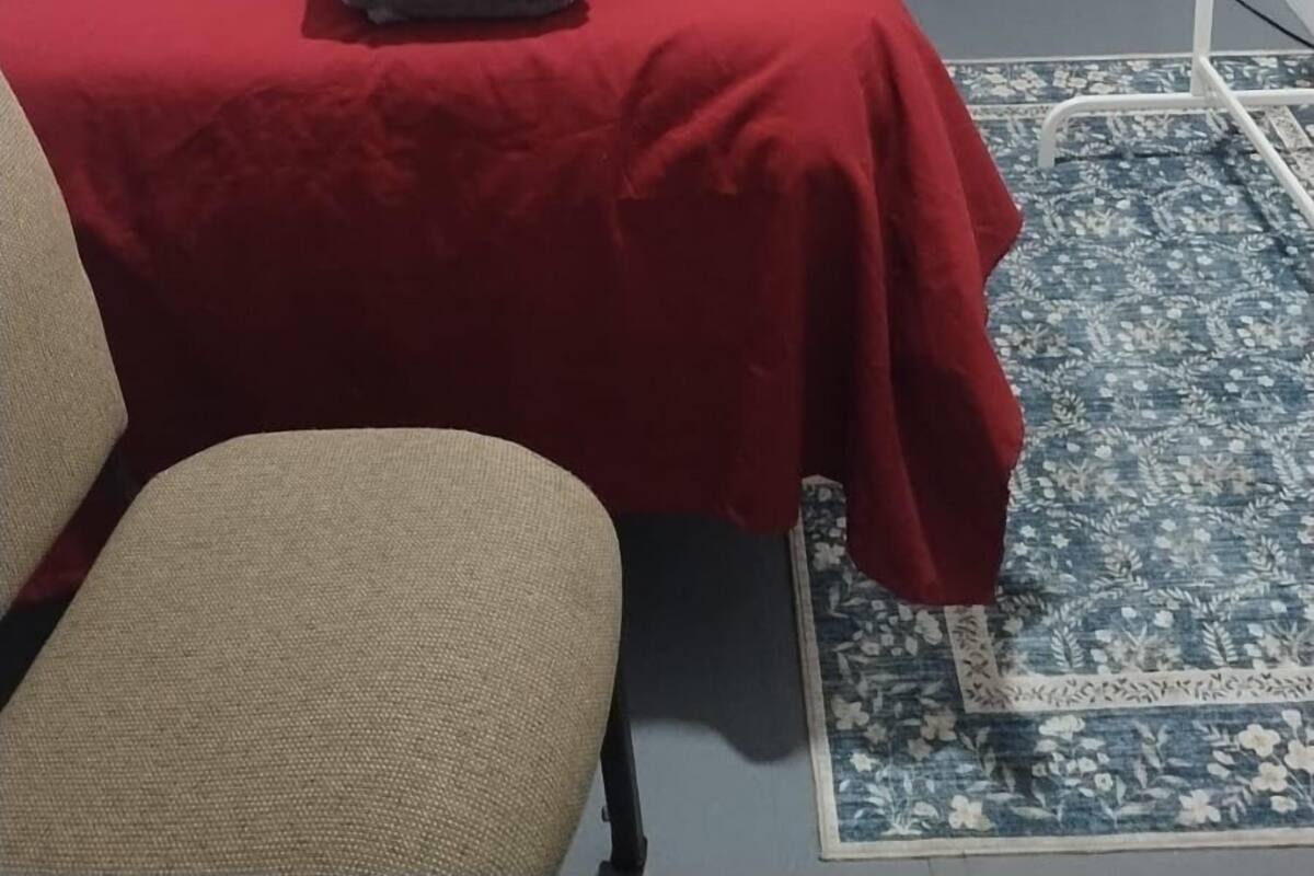 Ein Hotelzimmer mit einem Bett, einem Sessel, einem Nachttisch mit Lampe und einem roten Vorhang.