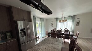 A kitchen with a large island, a refrigerator, and a dining area with a table and chairs.