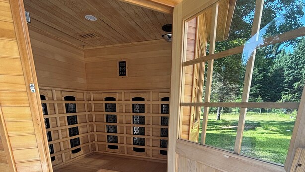 A sauna with multiple benches, a ventilation system, and a view of a green landscape through a window.