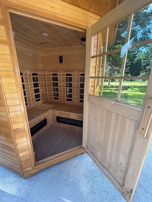 Un sauna doté de plusieurs bancs, d’un système de ventilation et offrant une vue sur un paysage verdoyant par une fenêtre.