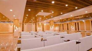 Un amplio hall de hotel con filas de asientos blancos, techo de madera e iluminación moderna.