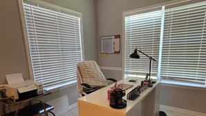 A home office with a desk, chair, and large windows with blinds. - The StayHaus, 
Relax in this stylish home! (Horn Lake)