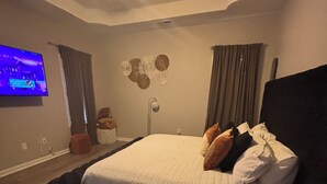 A bedroom with a bed, a ceiling fan, a TV, and a wall-mounted light fixture. - The StayHaus, 
Relax in this stylish home! (Horn Lake)