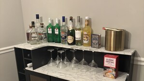A bar area with various liquor bottles, glasses, and a whiskey decanter. - The StayHaus, 
Relax in this stylish home! (Horn Lake)