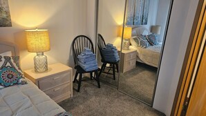 Et soveværelse med en seng, to sengeborde, en stol, et spejl og et natbord med en lampe.