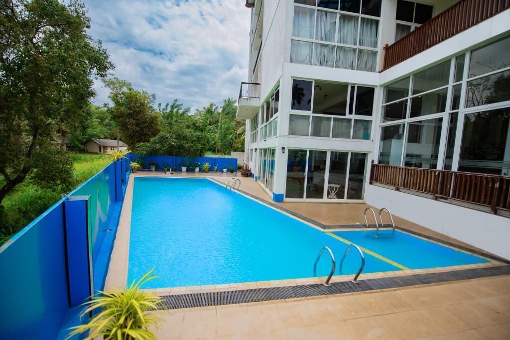 A modern building with a swimming pool, large windows, and a blue exterior wall.
