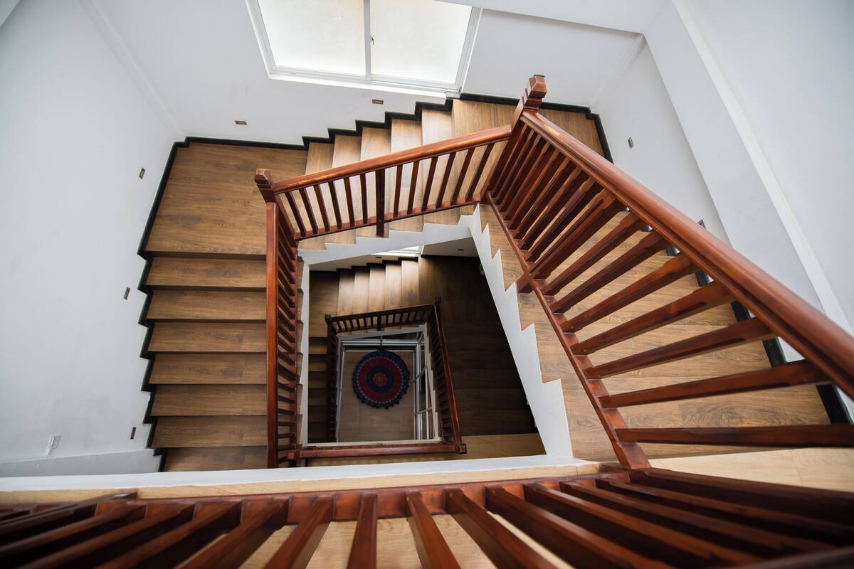 A wooden staircase with a skylight above, leading to a room with a circular patterned rug.