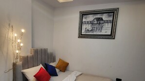 A modern bedroom with a bed, bedside table, lamp, and a framed picture on the wall. - Cozy Modern Studio Apartment in Ikoyi (Lagos)