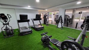 A gym with treadmills, an elliptical, and weightlifting equipment on artificial grass. - Cozy Modern Studio Apartment in Ikoyi (Lagos)