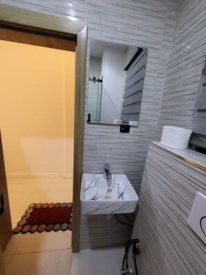 Een badkamer met een marmeren wastafel, een spiegel en een handdoekhouder.