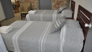 A hotel room with two beds, a brick wall, and a wooden door. - GARAL House: Rayón 77 (Morelia)