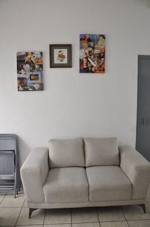 Un soggiorno con un divano color beige, un quadro incorniciato e un collage a parete.
