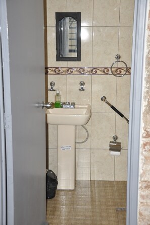 Un bagno con lavandino, specchio, portasciuga e porta carta igienica.