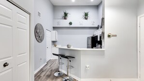Una cocina moderna con barra, muebles de cocina blancos y salpicadero gris.