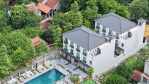 Vista aérea de uma área residencial com piscina, um pátio com cadeiras de descanso e um pequeno jardim.