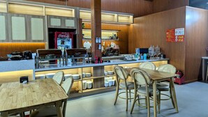 Interior de restaurante com painéis de madeira, um refrigerador Coca-Cola e um balcão com diversos itens.