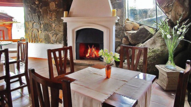 Un comedor con chimenea, paredes de piedra y mobiliario de madera.