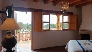 Un dormitorio con un ventanal grande, chimenea y una cama con cabecera decorativa.