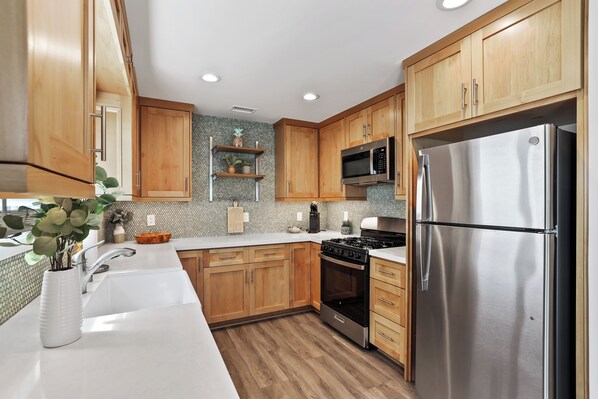 A modern kitchen with wooden cabinets, stainless steel appliances, and a tiled backsplash.
