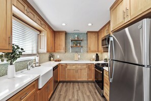A modern kitchen with wooden cabinets, a stainless steel refrigerator, and a tiled backsplash.