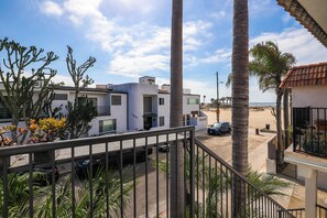 A residential area with modern houses, a street, and a beach in the background.