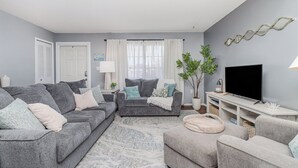 A living room with a grey sofa set, a TV, and a potted plant. - Charming 3-bedroom Pool House with WiFi and AC in Palm Bay (Palm Bay)