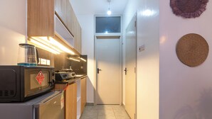 Una cocina pequeña con microondas, tostadora y cafetera. Se ve una puerta al fondo.