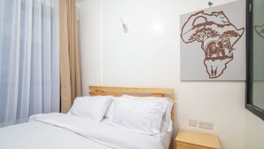 Un dormitorio con cama, mesita de noche de madera, enchufe y un interruptor de luz en la pared.
