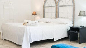 A neatly made bed with white linens, a bedside table with a lamp, and a window with a wooden frame. - Charming 3-bedroom house with AC, WiFi in amazing Hollywood (Hollywood)