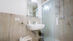 A bathroom with a white sink, a mirror, a glass shower enclosure, and a small shelf with toiletries. - Charming 3-bedroom house with AC, WiFi in amazing Hollywood (Hollywood)