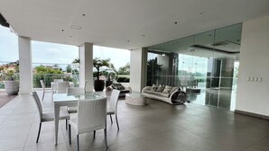 Un espace de vie spacieux et moderne, comprenant un coin repas, des canapés et une cloison en verre.