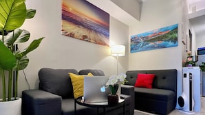 Un salon moderne avec deux canapés, une table basse, une plante en pot et des œuvres d’art accrochées aux murs.