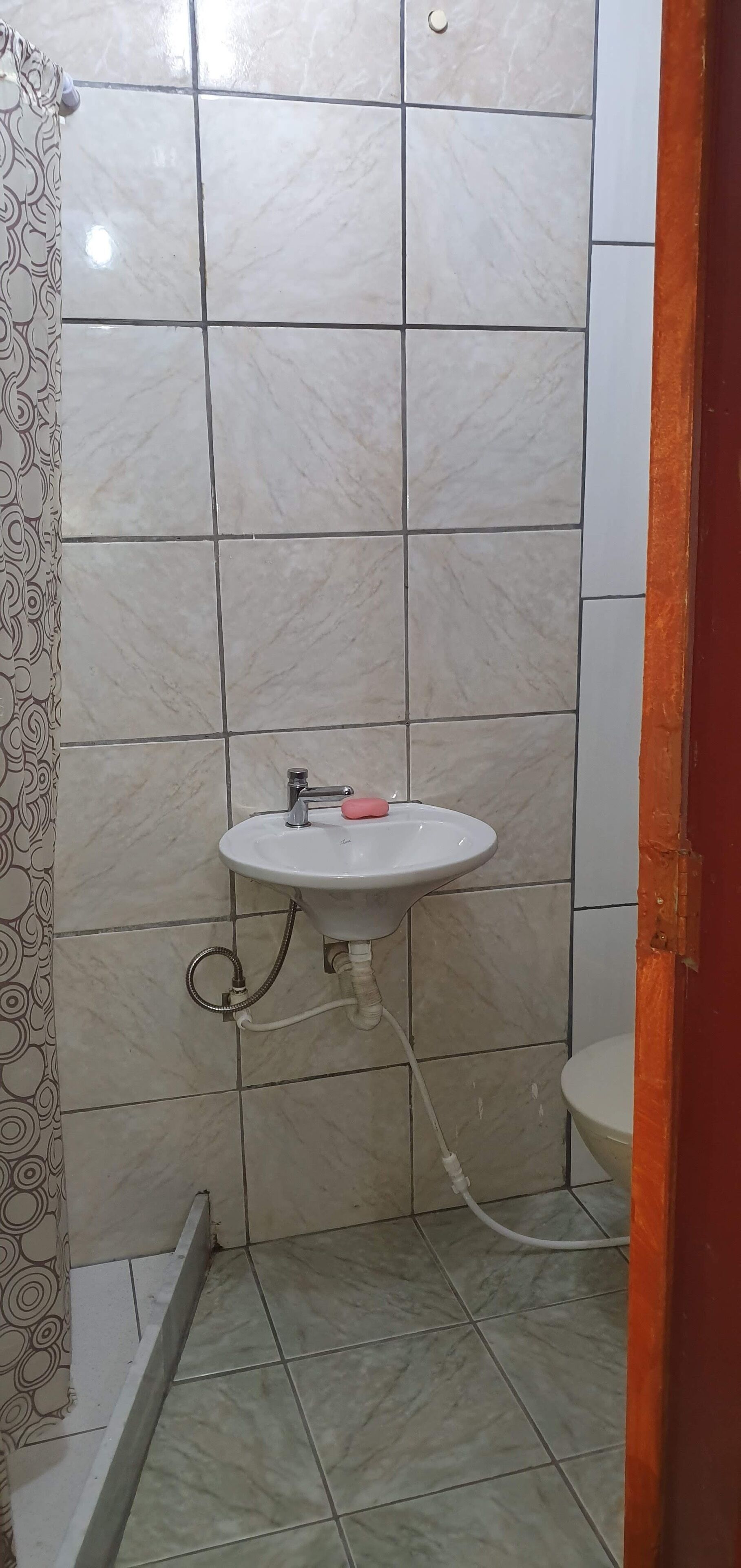A bathroom with a white sink, a shower curtain, and a toilet.