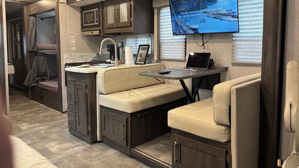 A compact RV interior with a kitchenette, a flat-screen TV mounted on the wall, and seating areas. - Spacious RV in Brilliant Broken Bow with AC, WiFi, near Day Spa and Winery! (Broken Bow)