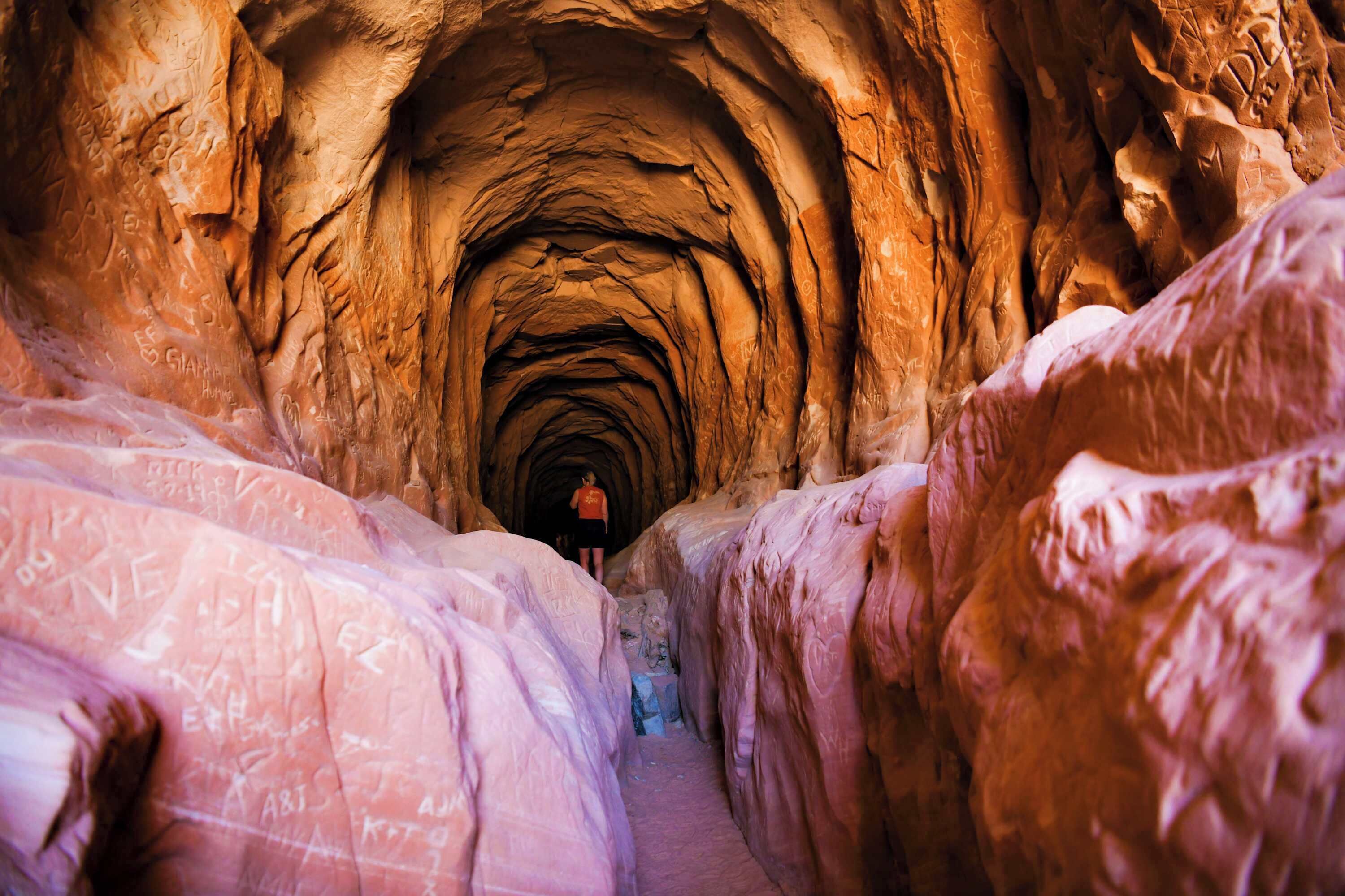 A narrow, rocky passageway with inscriptions on the walls.