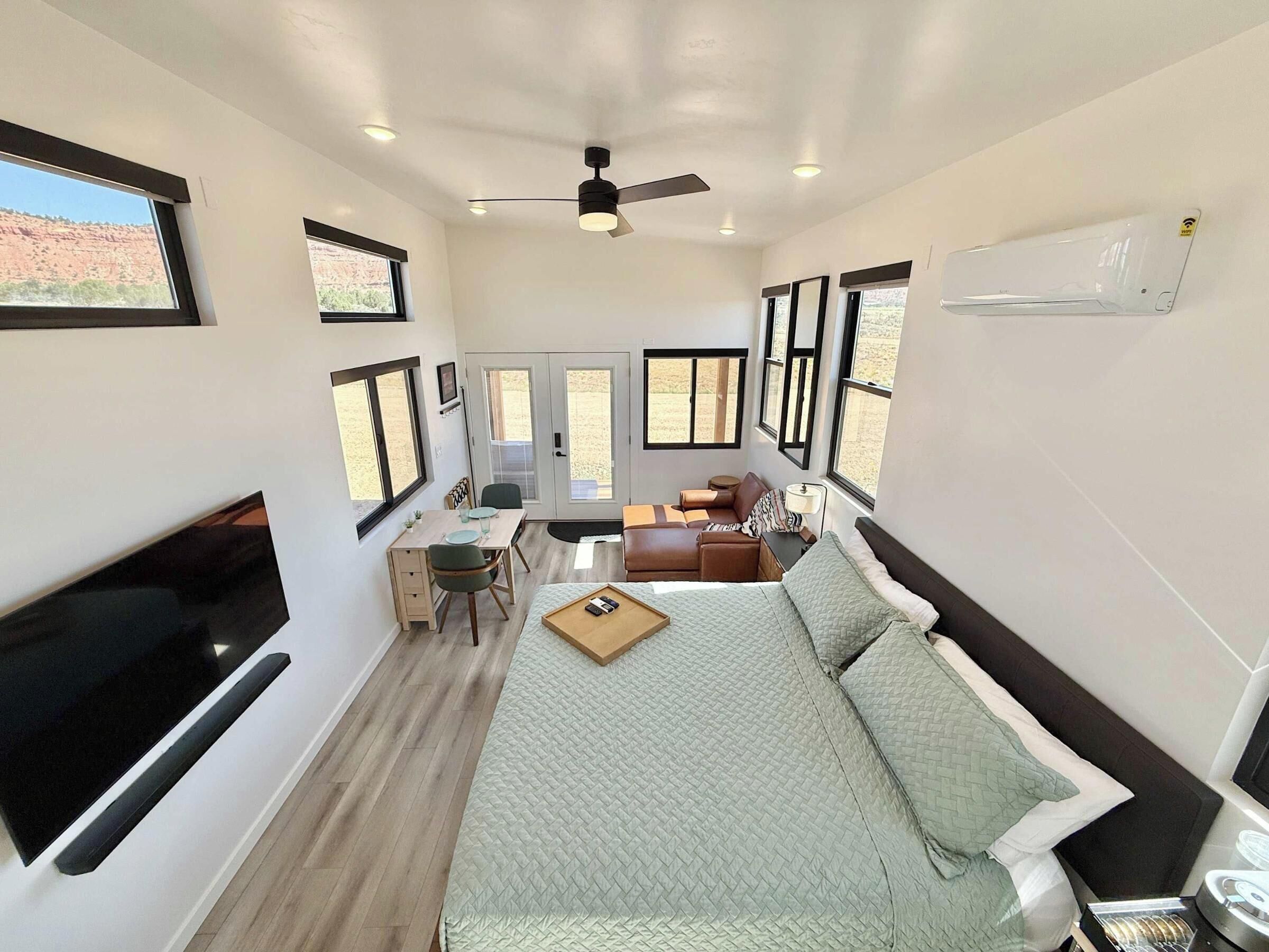 A compact, well-lit room with a bed, seating area, and a TV.