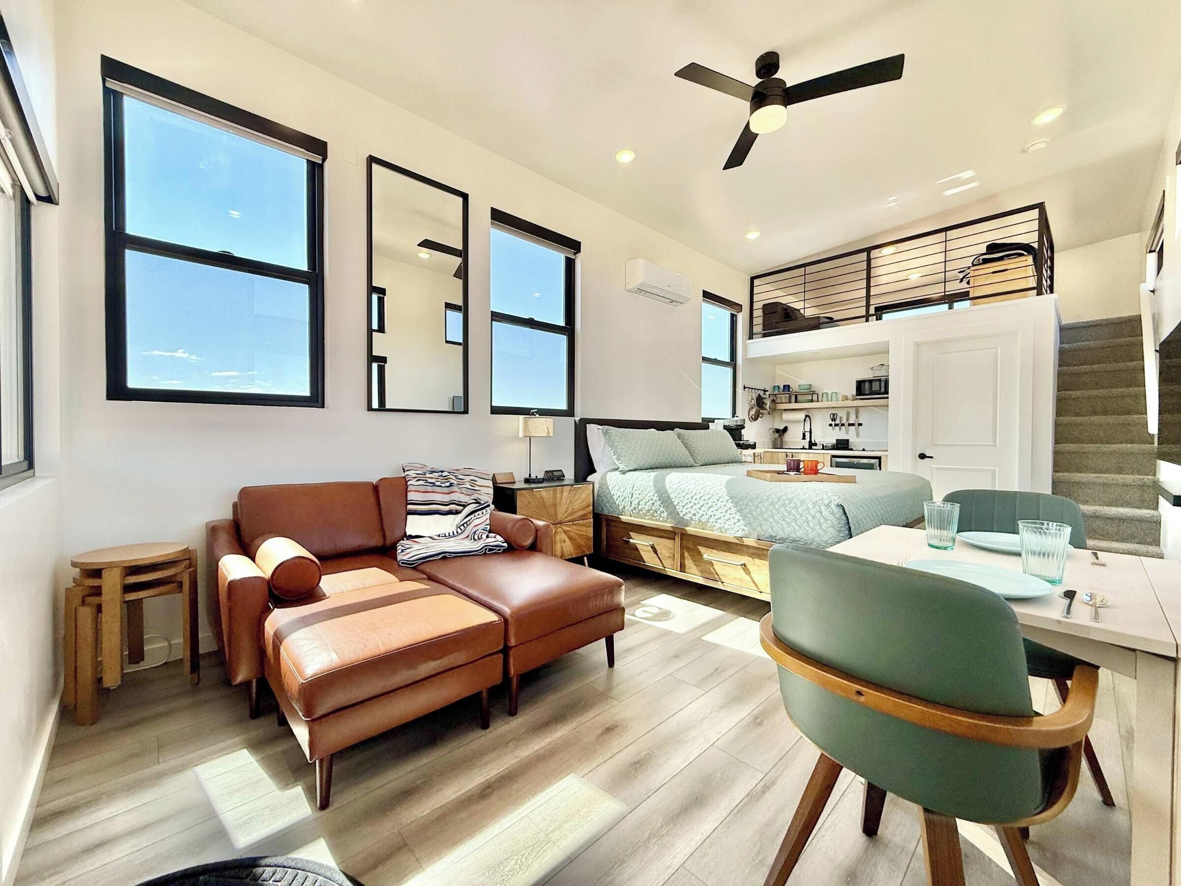 Um apartamento moderno com cozinha no estilo loft, um sofá, uma mesa de jantar e uma cadeira.