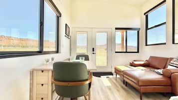 A modern interior with a desk, chair, sofa, and large windows offering a view of the desert landscape.