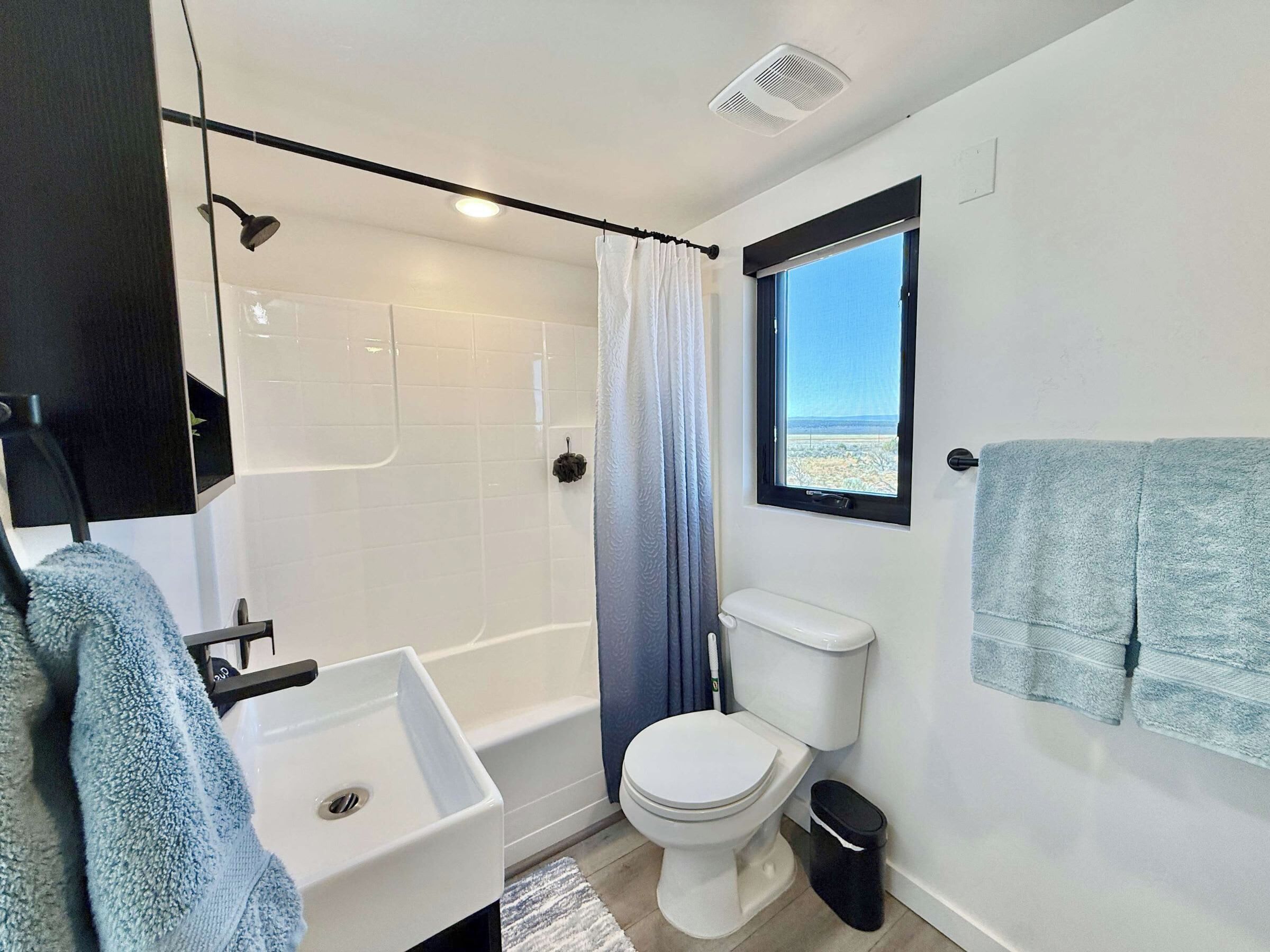 Un baño con bañera, inodoro, lavamanos y ventana con vistas.