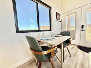 A dining area with a table, chairs, and a window with a view of a building and landscape.