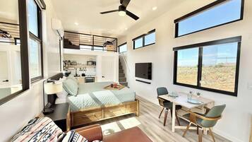 Ein modernes Interieur mit Bett, Sitzgelegenheit, Essbereich und Küche.