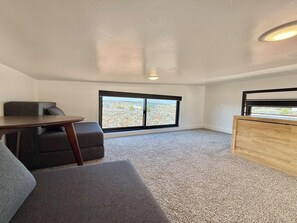 A room with a large window, a sofa, a small table, and a wooden cabinet.