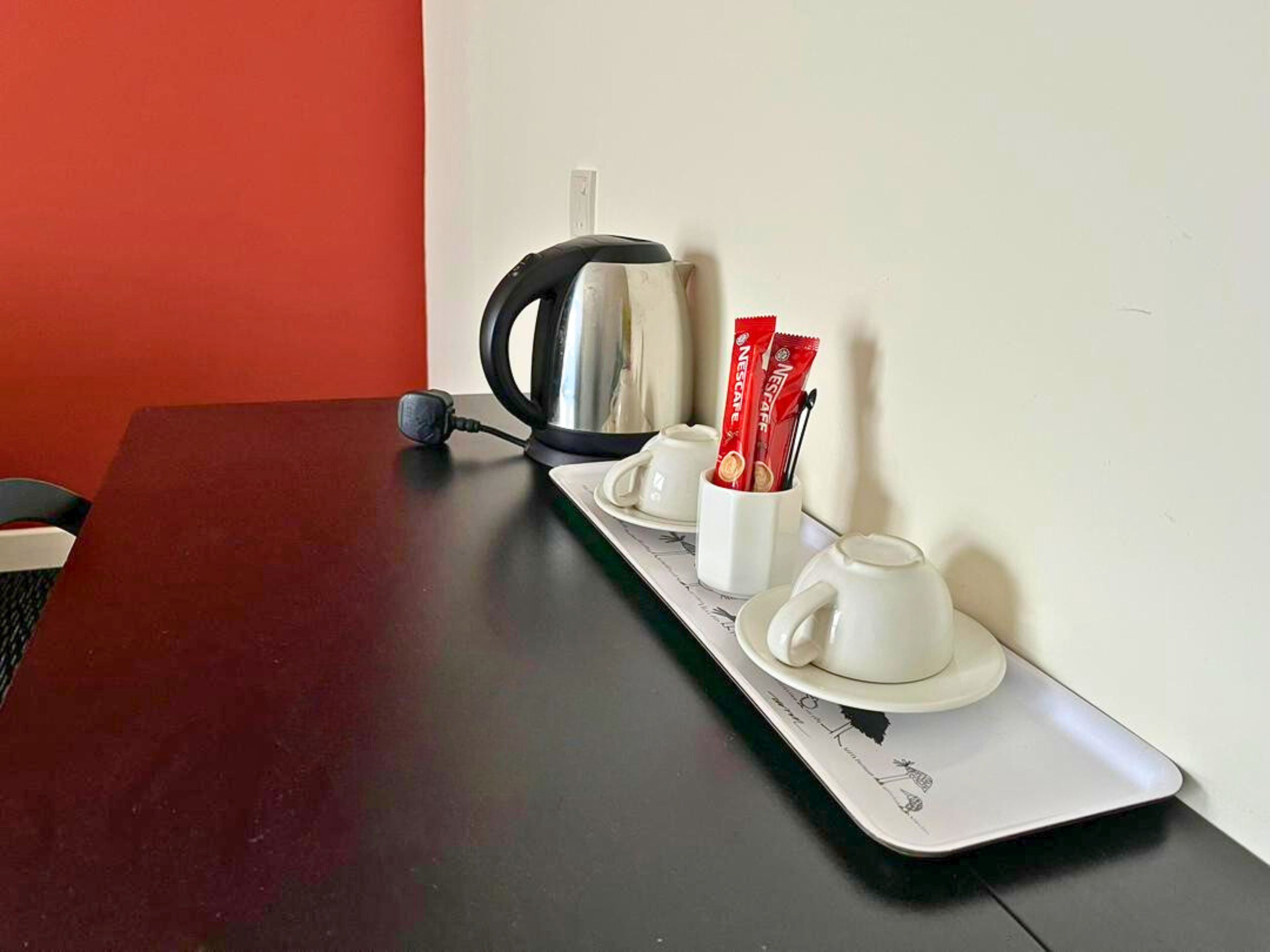 Une table avec une bouilloire, deux tasses et deux sachets de café Nescafé.