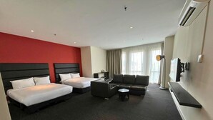 A hotel room with two beds, a sofa, a coffee table, and a TV. - The Estella Hotel Klang (Klang)